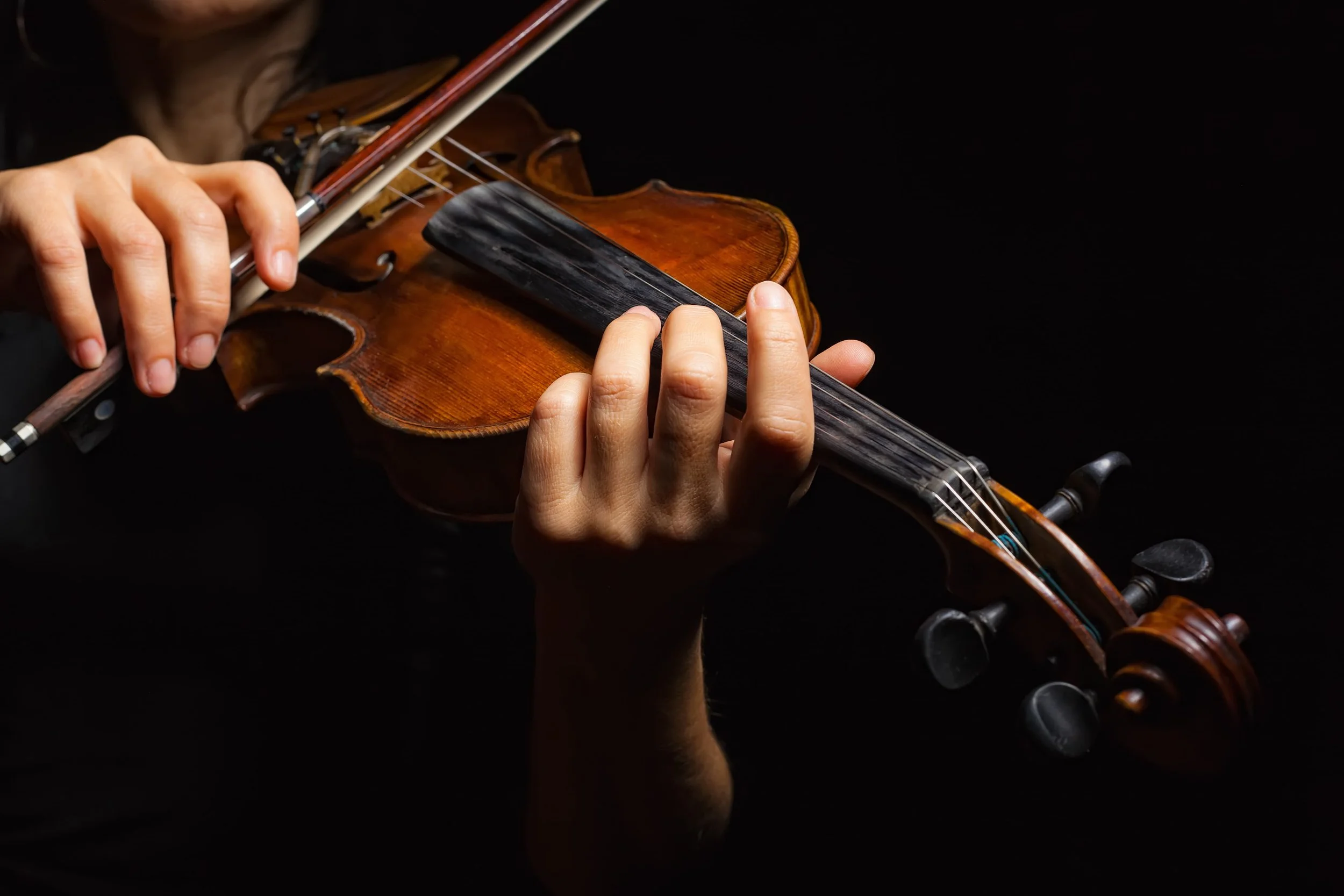 A close-up of hands playing the violin with a bow in London.
