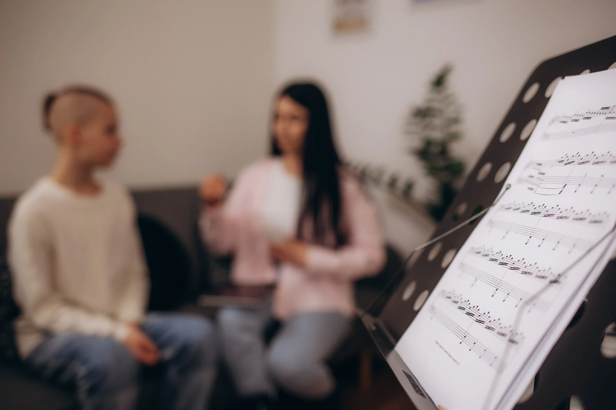 A young girl having a singing lesson with sheet music on a music stand.