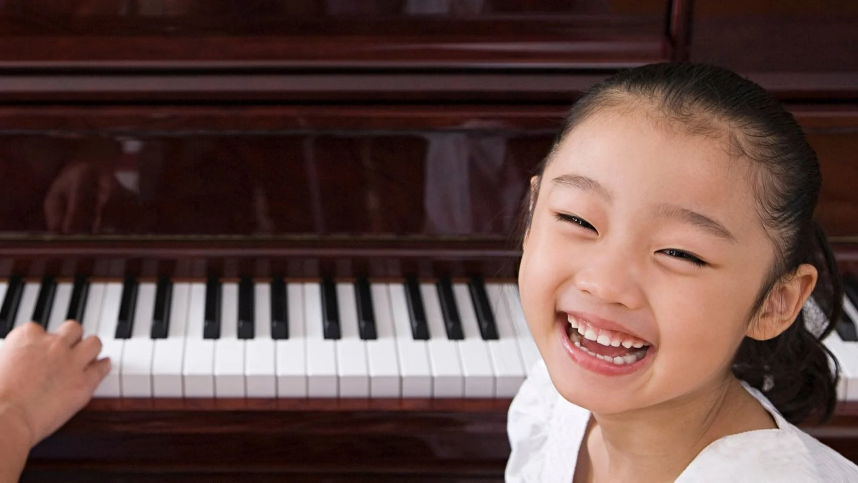 Very happy girl during her piano lesson at home in London.