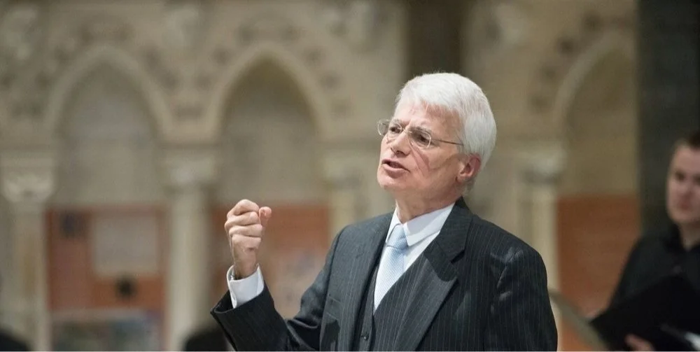 Ralph Allwood conducting an orchestra of instruments.