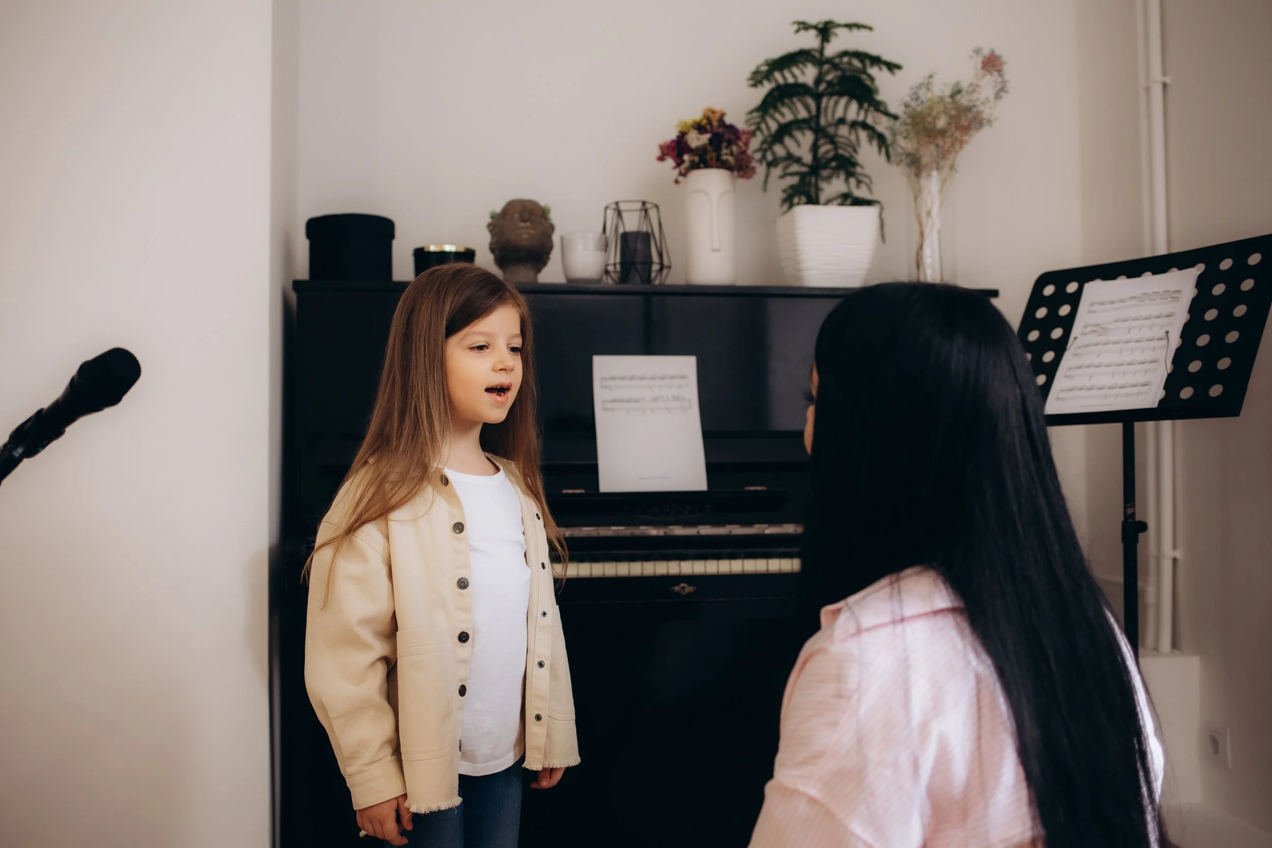 A young girl having a singing lessons with a female music teacher.