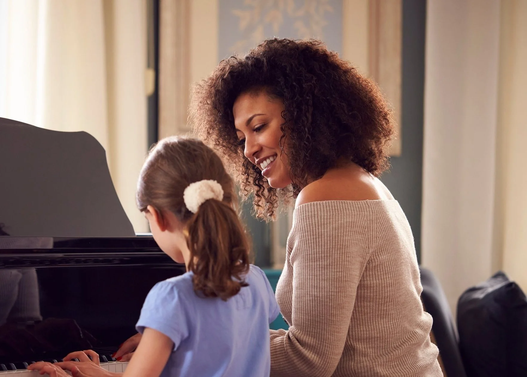 A woman giving a young girl a piano lesson.