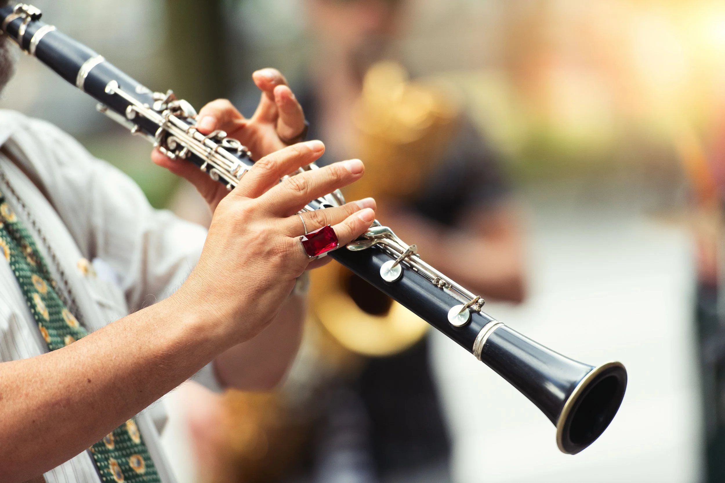 Close-up of hands playing a clarinet with an orchestra.