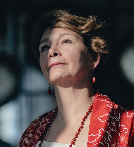 Portrait of Martha Collard, founder of Red Doors Studio, in a red patterned jacket.