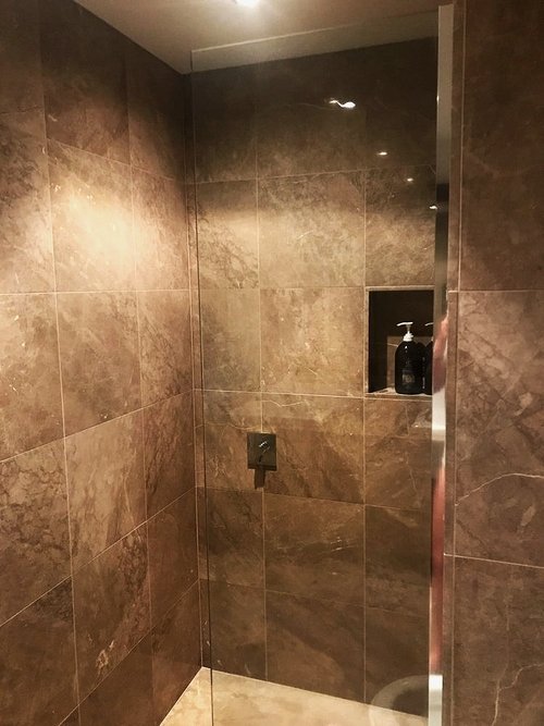 A tiled, walk in shower, featuring a stylish, tiled soap box. these showers are easy to clean, and help create a beautiful bathroom experience.