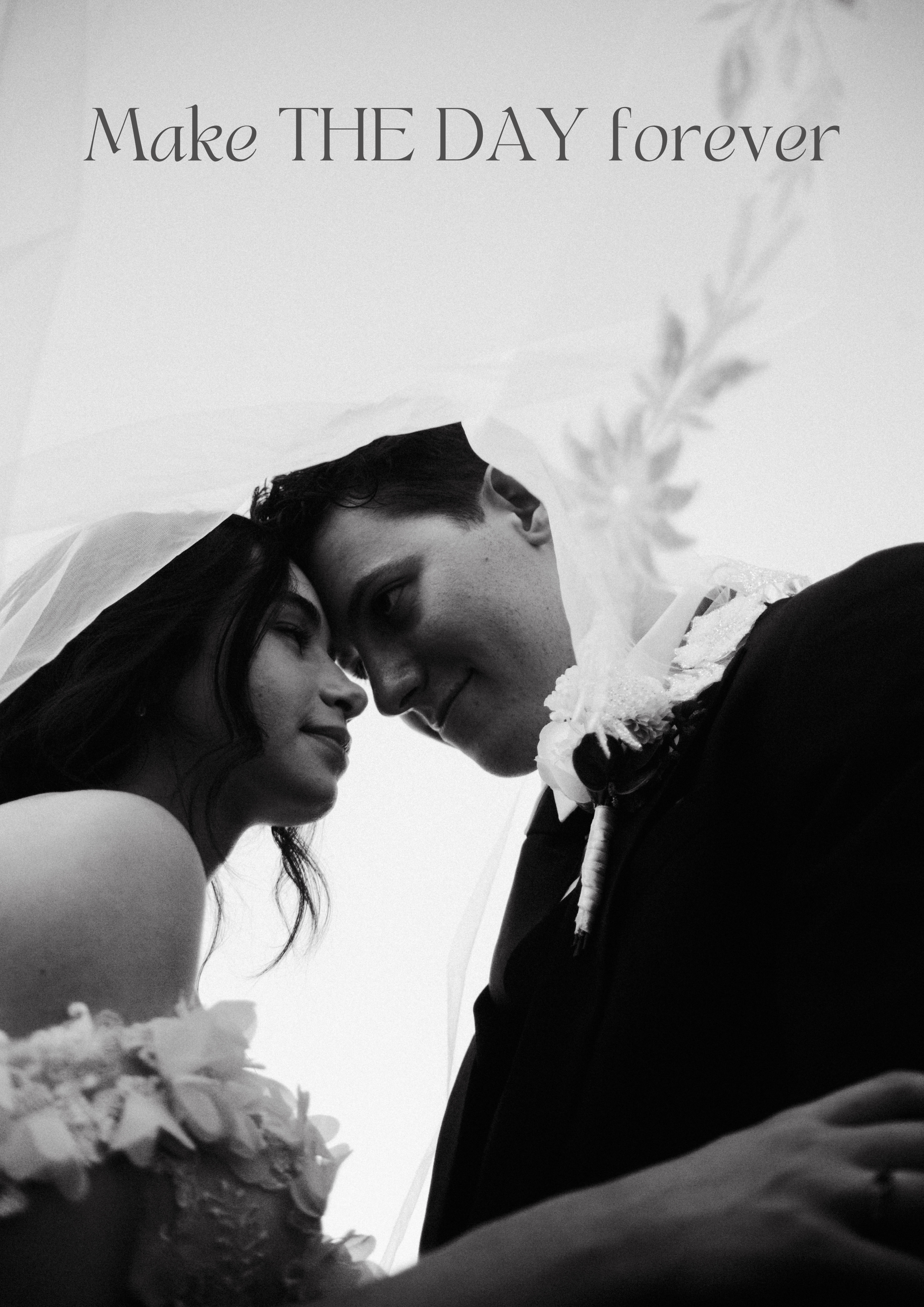 Black-and-white photo of a bride and groom with foreheads touching, smiling softly, with the bride holding a bouquet in the foreground and the groom wearing a boutonniere. The background contains a soft, out-of-focus floral decoration and text readin