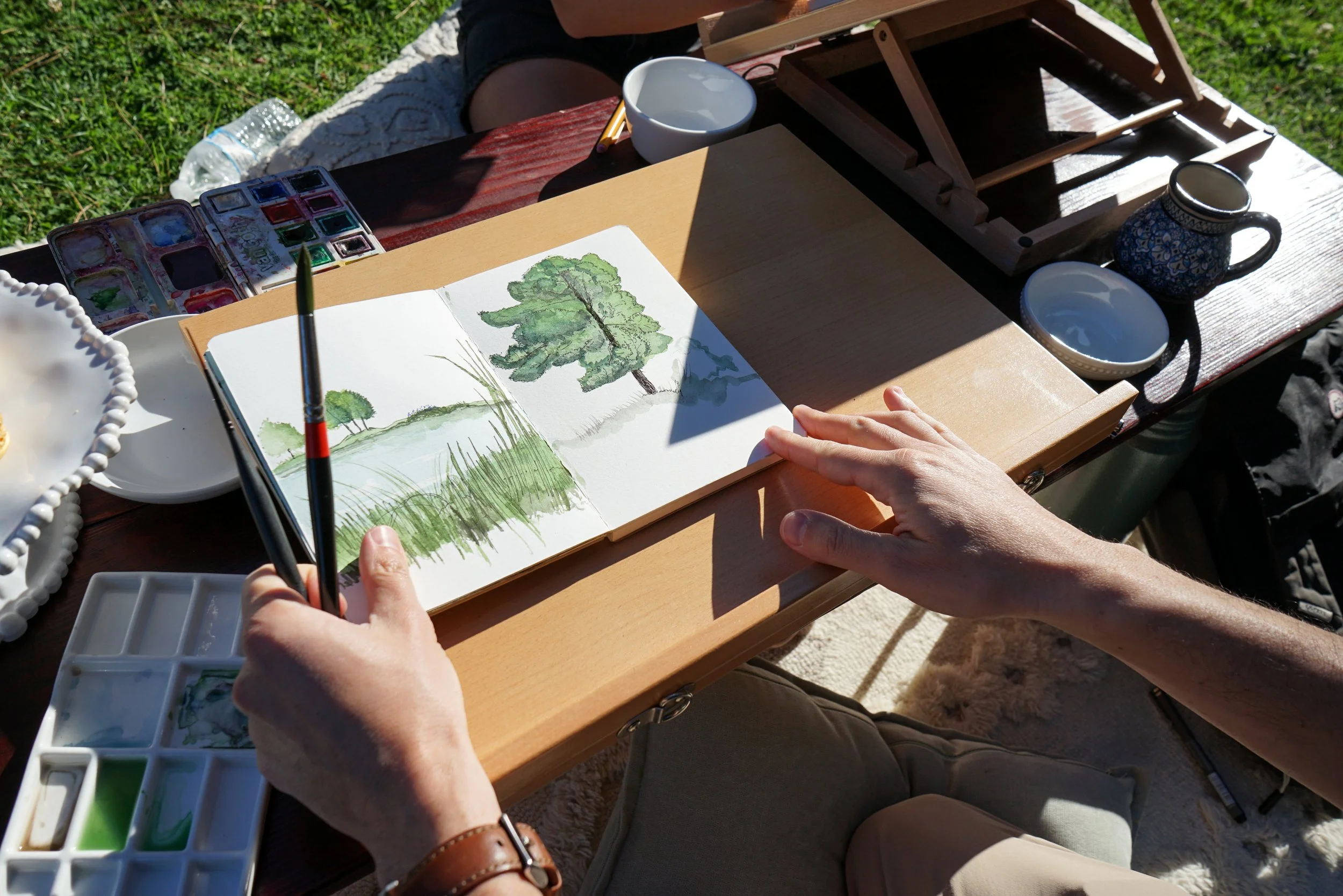 A man's watercolor painting of a tree and a meadow at a Park in San Diego