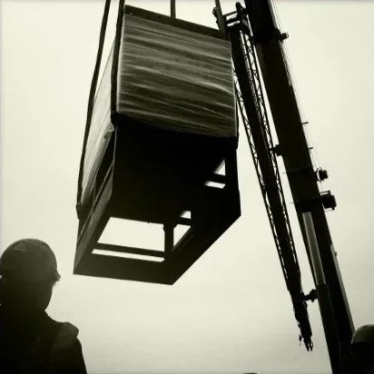 A member of the CIS team is watching a load be lifted overhead by a crane