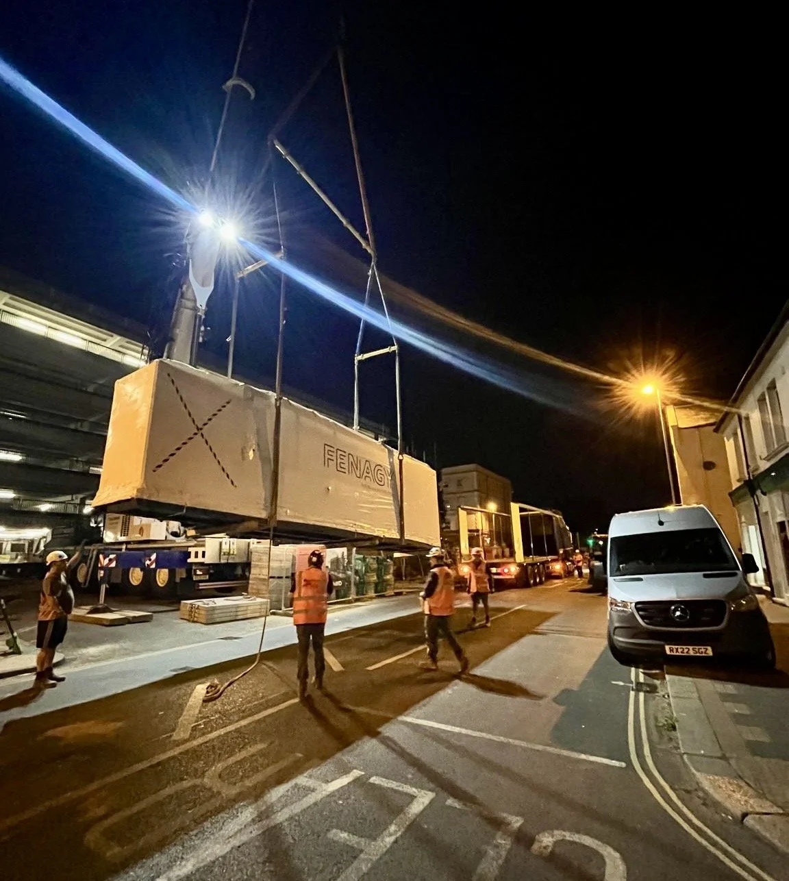 A tall rig moving a large piece of equipment in a dark night setting.