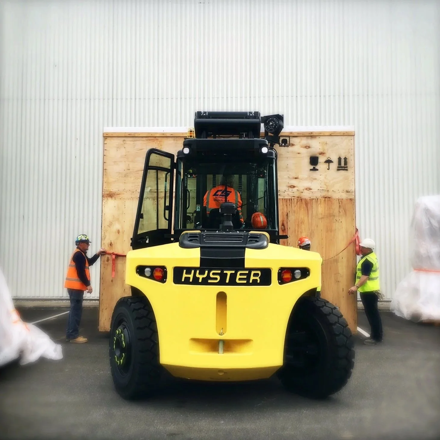 The JBC CIS team are on site, there are two men either side of a large piece of boxed equipment which is being moved by truck.