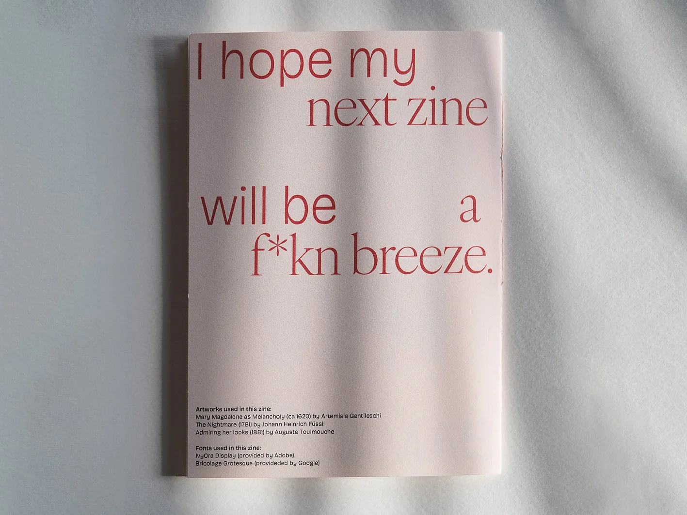 En försättsblad eller baksida av en zine med texten 'I hope my next zine will be a f*kn breeze' i stort röd text. Nedtill står det information om konstverken och typsnitt som används.