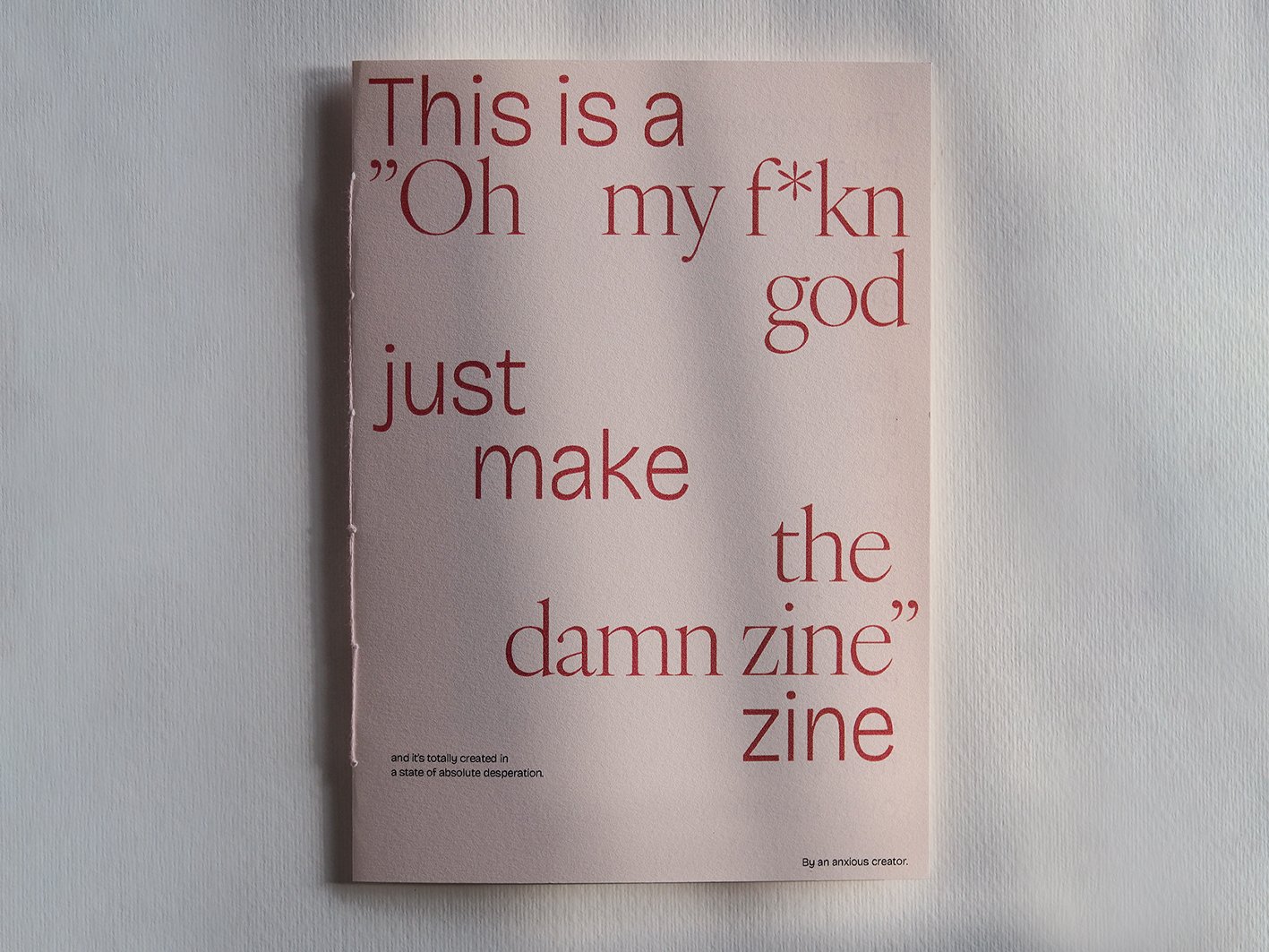 En rosa affisch med texten: "This is a 'Oh my f*kn god' just make the damn zine" på en vit vägg.