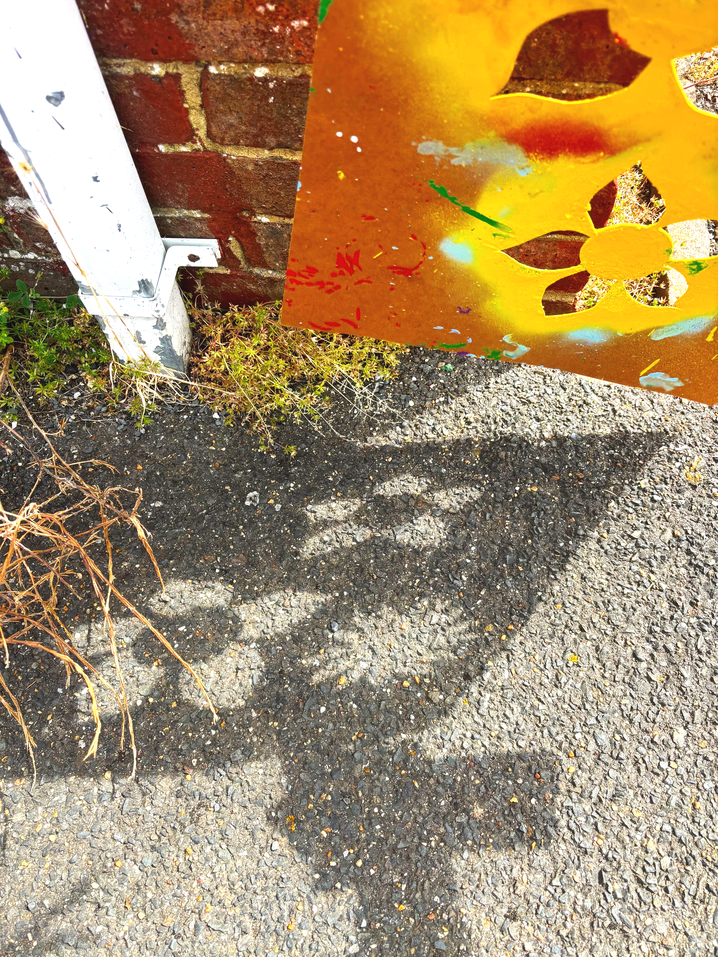  stencil sheets of flowers with residue paint where they have been used and placed on the floor outside with a shadow of a person looking at them