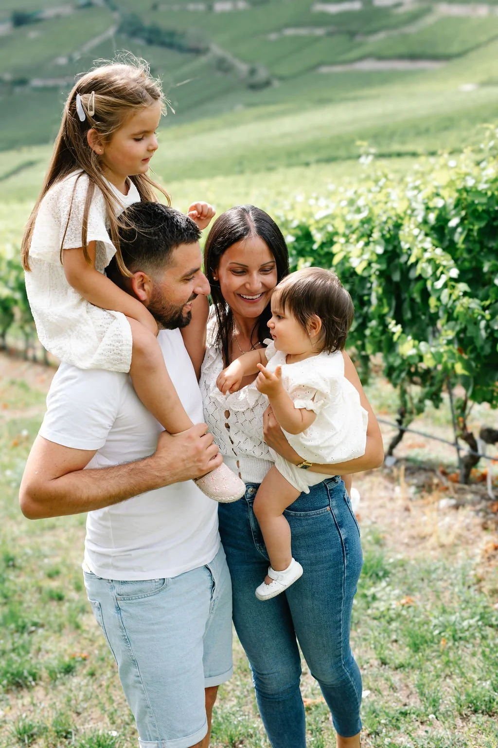 Une famille heureuse dans un vignoble vert, composée d'un père, d'une mère et deux jeunes filles, profitant d'une journée en plein air.
