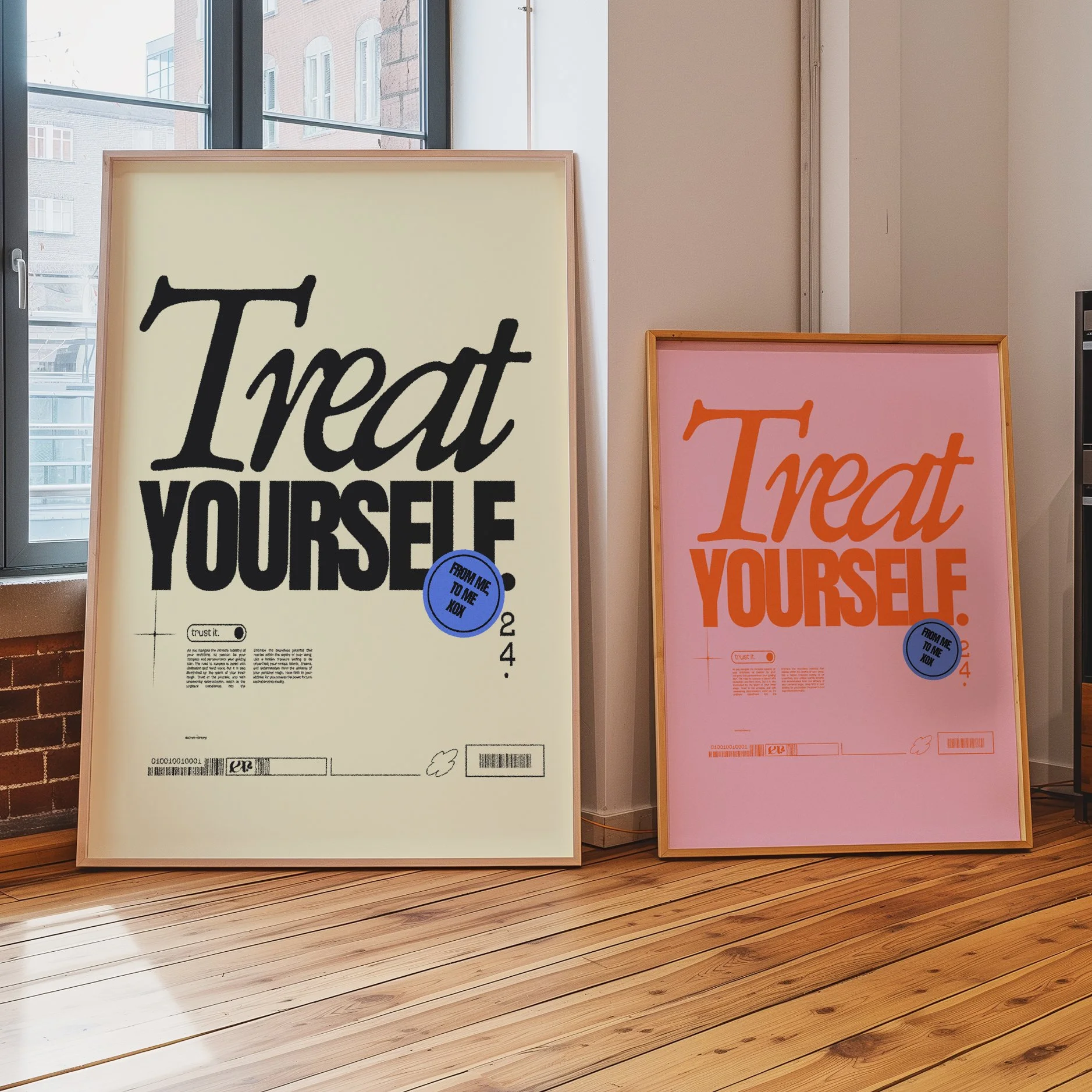 Two framed posters on a hardwood floor, one with a cream background and black and blue text reading 'Treat Yourself,' and the other with a pink background and orange and blue text also saying 'Treat Yourself.'