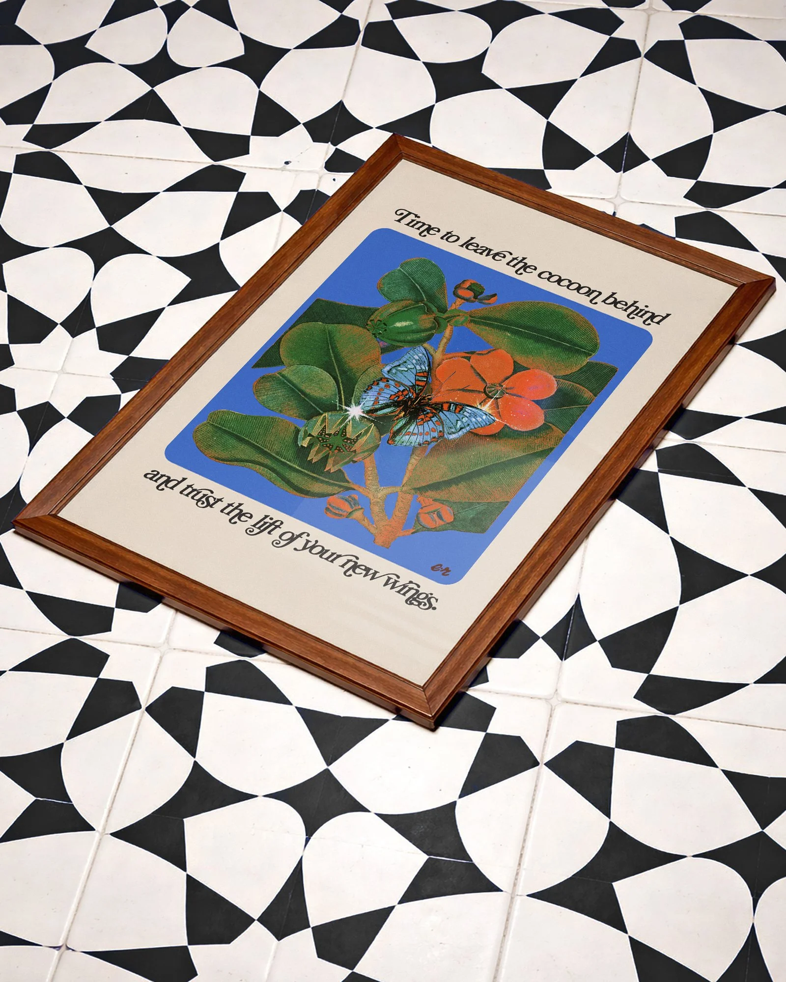 A framed poster on a black and white tiled floor, featuring an illustration of a butterfly, a caterpillar, and leaves with the text "Time to leave the cocoon behind and trust the lift of your new wings."