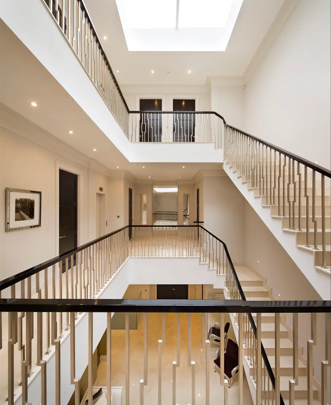 Interior view of a multi-story, modern building with staircases, railings, and an open ceiling with skylights.