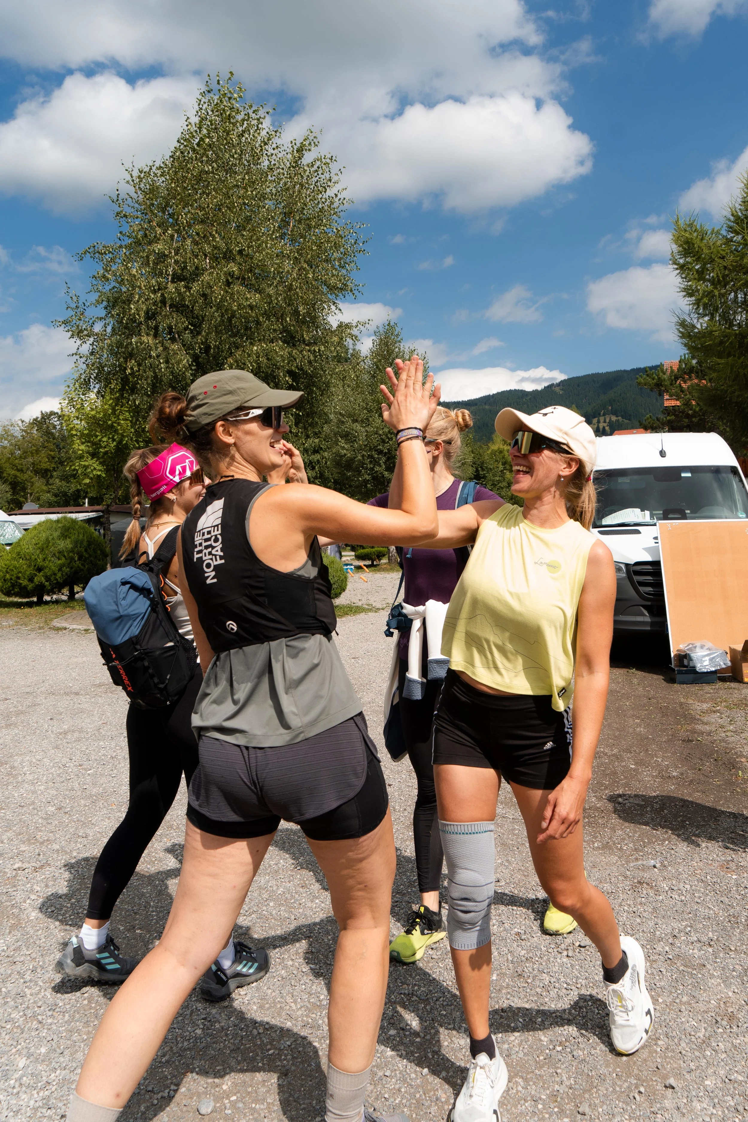 Zwei Frauen passen sich beim High Five an, während sie draußen in sportlicher Kleidung laufen.