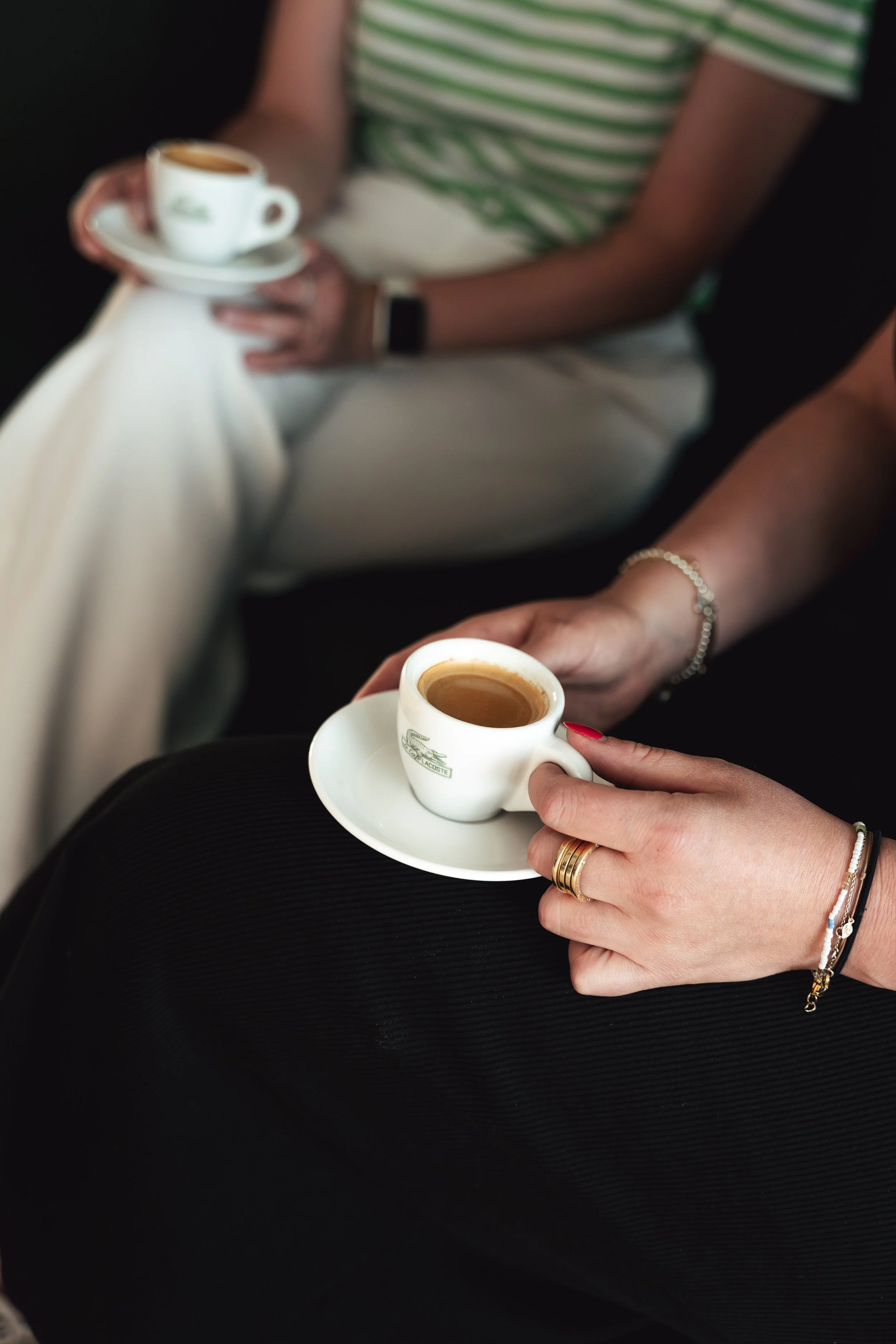 Zwei Frauen halten kleine Tassen Kaffee, beim Entspannen in einem Café