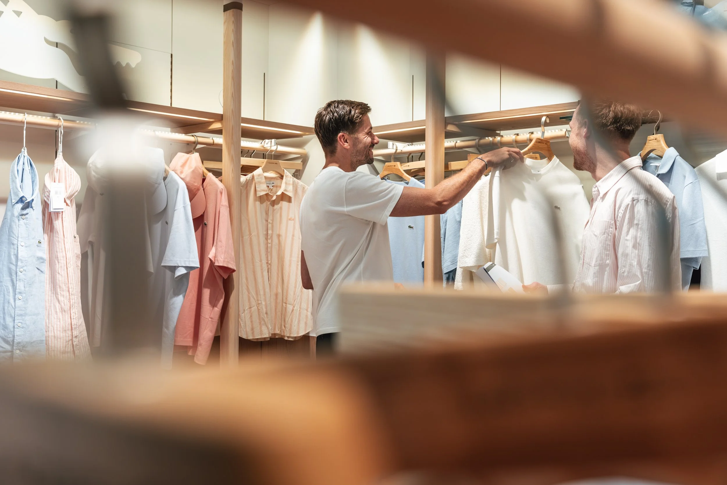 Zwei Männer in einem Kleidungsgeschäft, die sich Shirts anschauen.