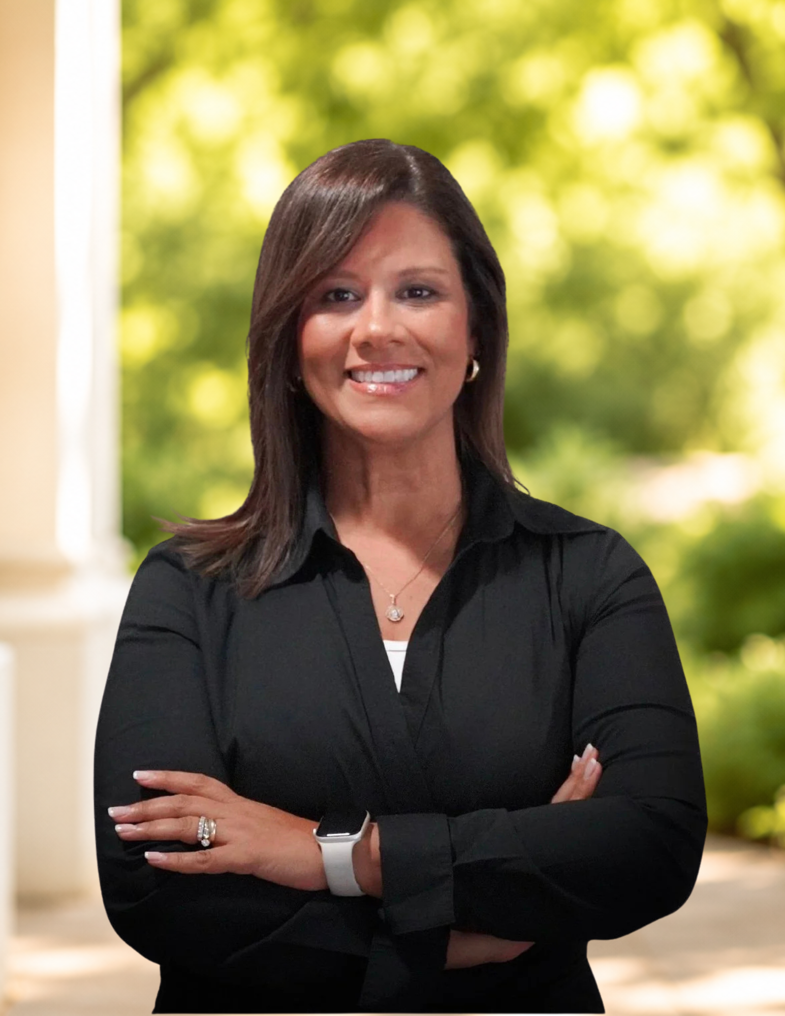 Smiling person in a black shirt crossing arms, wearing a smartwatch and jewelry, against a gray background.