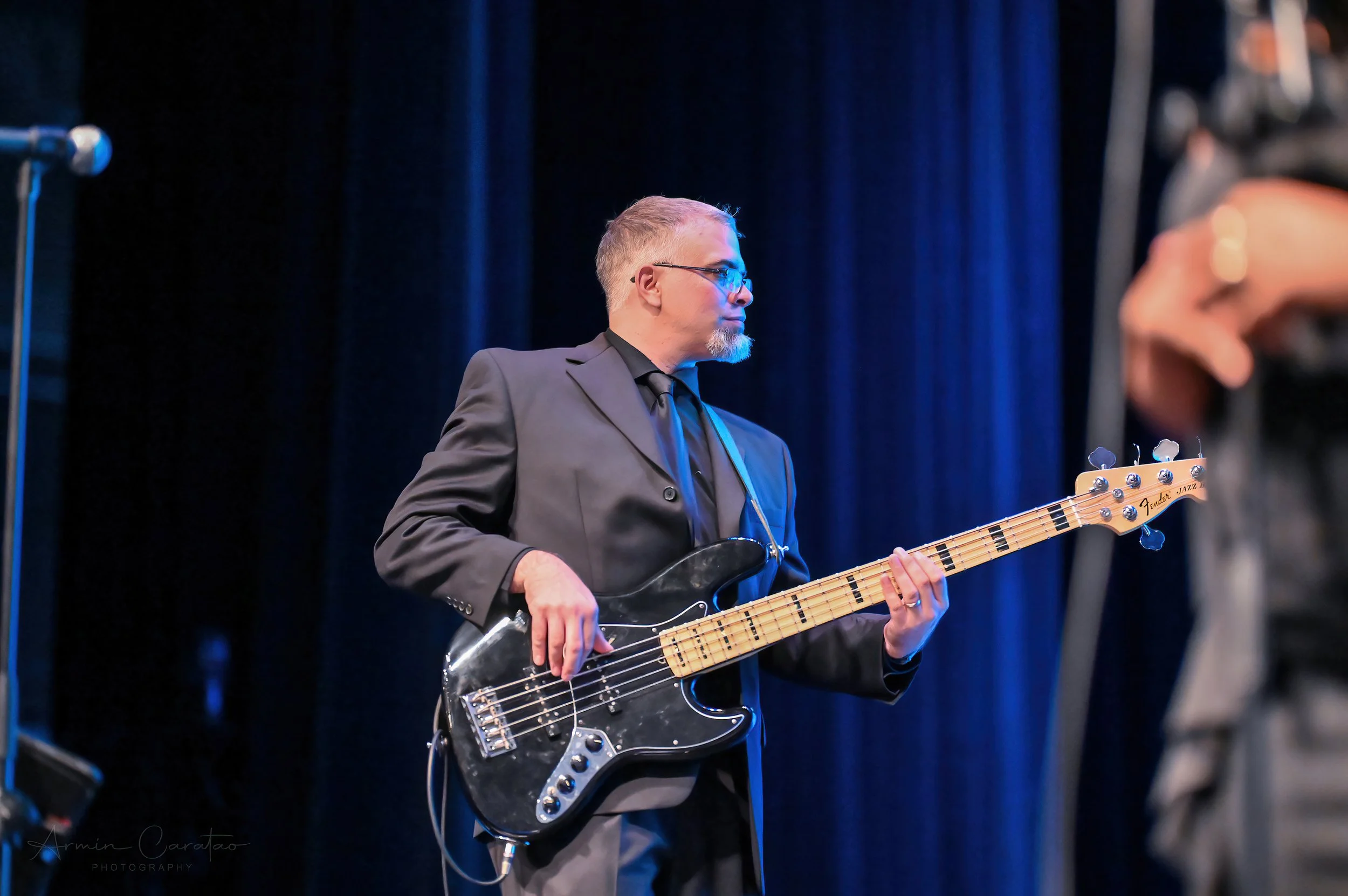 Musician playing a black bass guitar on stage