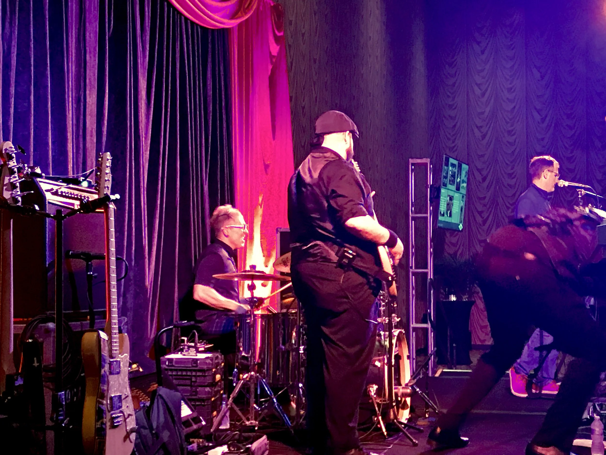 Live stage performance with musicians playing drums and guitars