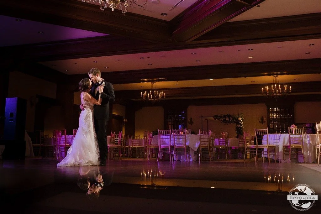 Bride and groom dancing in an elegant dimly lit reception hall.