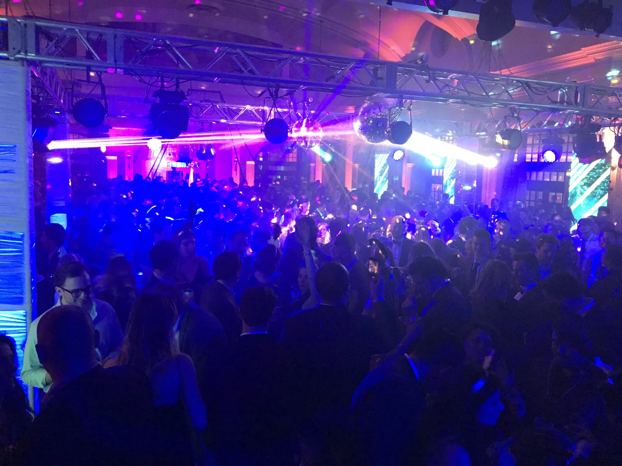 Crowded nightclub with colorful lights and a large group of people dancing