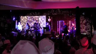 Band playing on stage with colorful lights and audience in chef hats