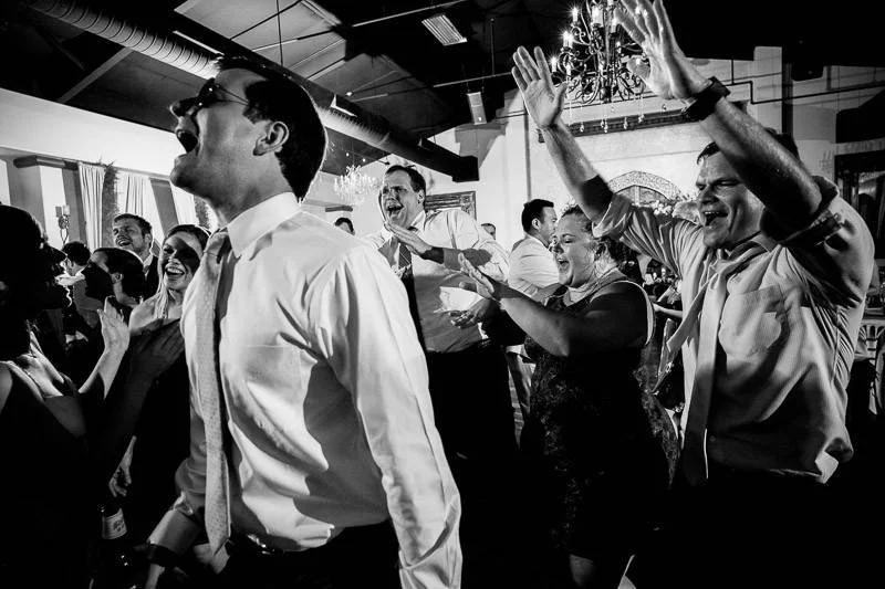 A lively group of people celebrating indoors, expressing joy and excitement in a black and white photo.