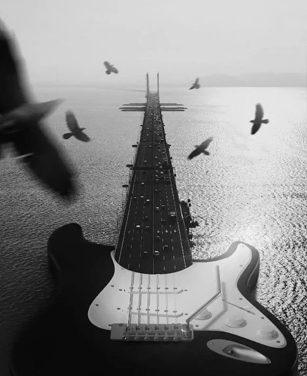 An edited image depicting a bridge over water that resembles an electric guitar, with birds flying overhead.
