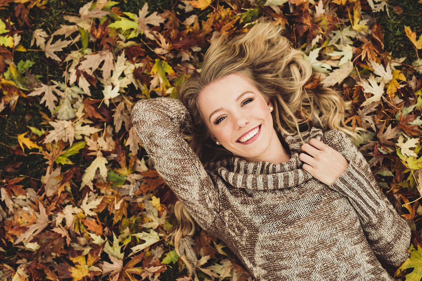 Senior girl laying on fall leaves at her family farm in Sunnyside, WA — soft light, earthy tones, and a cozy autumn fe