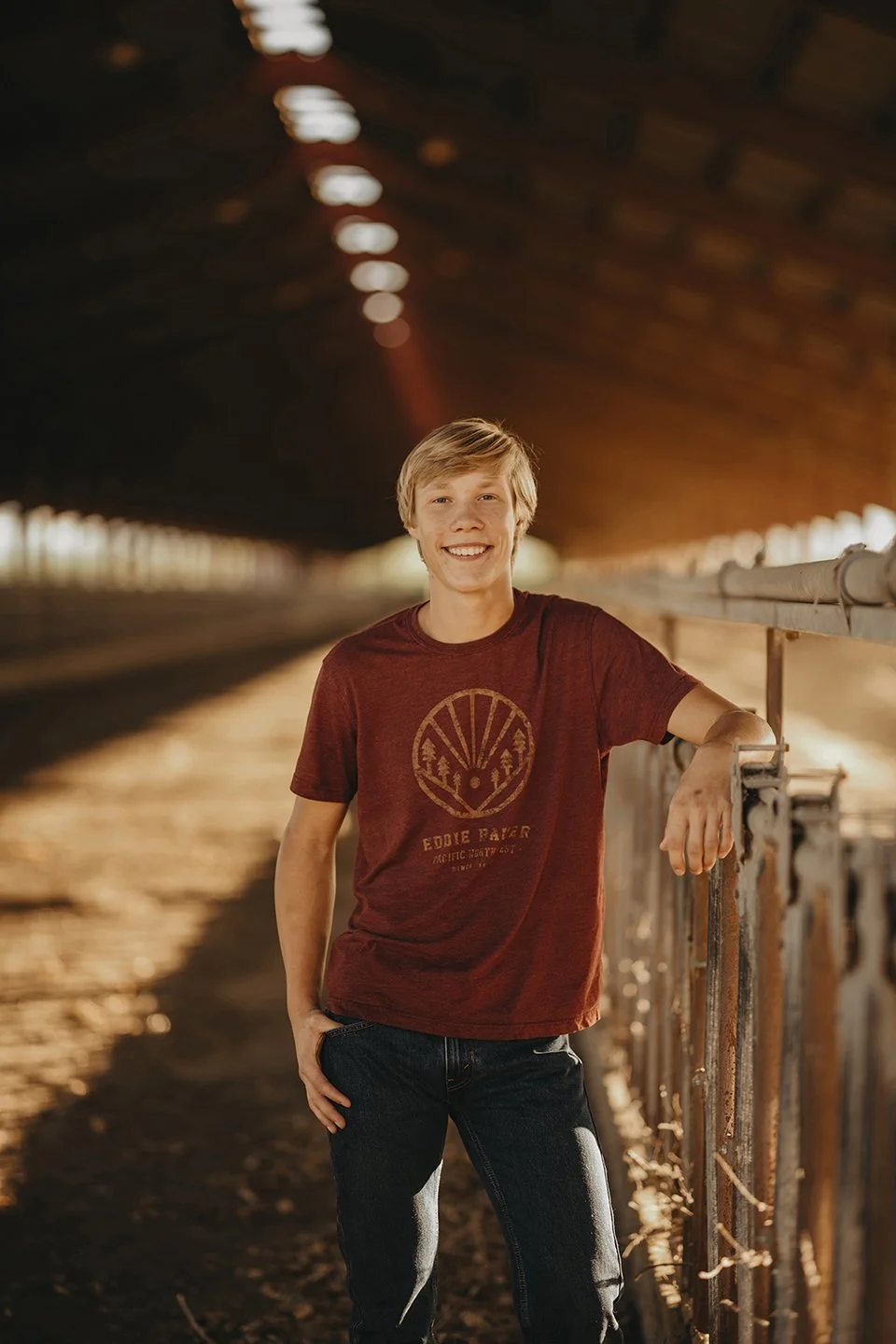 Golden-hour senior portrait of a young man at the family feeding station in Outlook, WA — warm light, country textures, and a relaxed, natural feel.