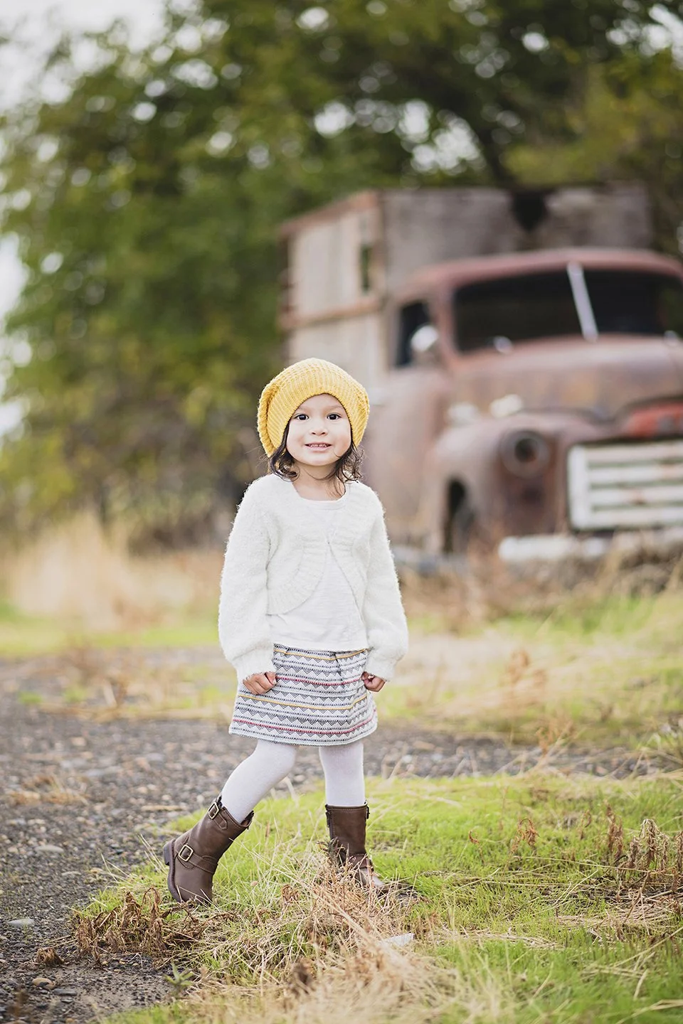 A cute portrait of Coco, age 3, smiling in front of a charming old truck in Mabton,WA.