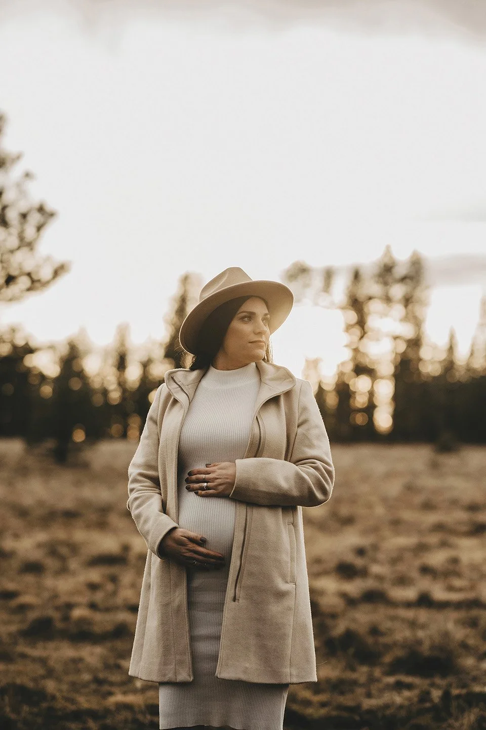 Soft evening light and earthy tones set the scene for this elegant Goldendale maternity portrait, where the mother-to-be looks away gently while holding her belly.