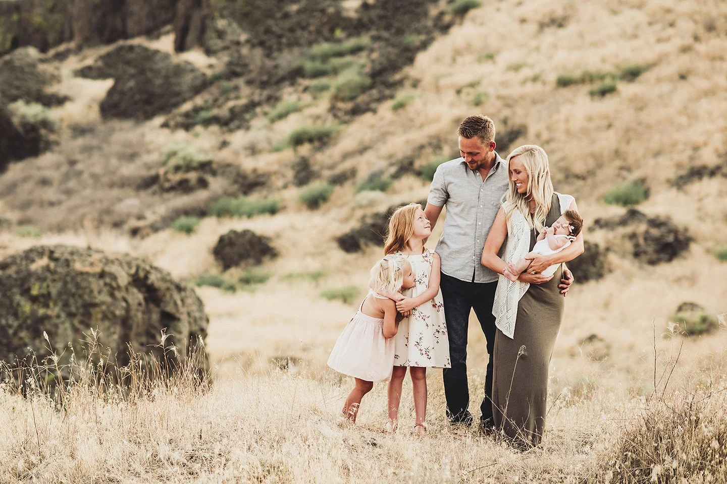 A tender family moment in Benton City, WA with parents and their kids all sharing smiles around their new baby.