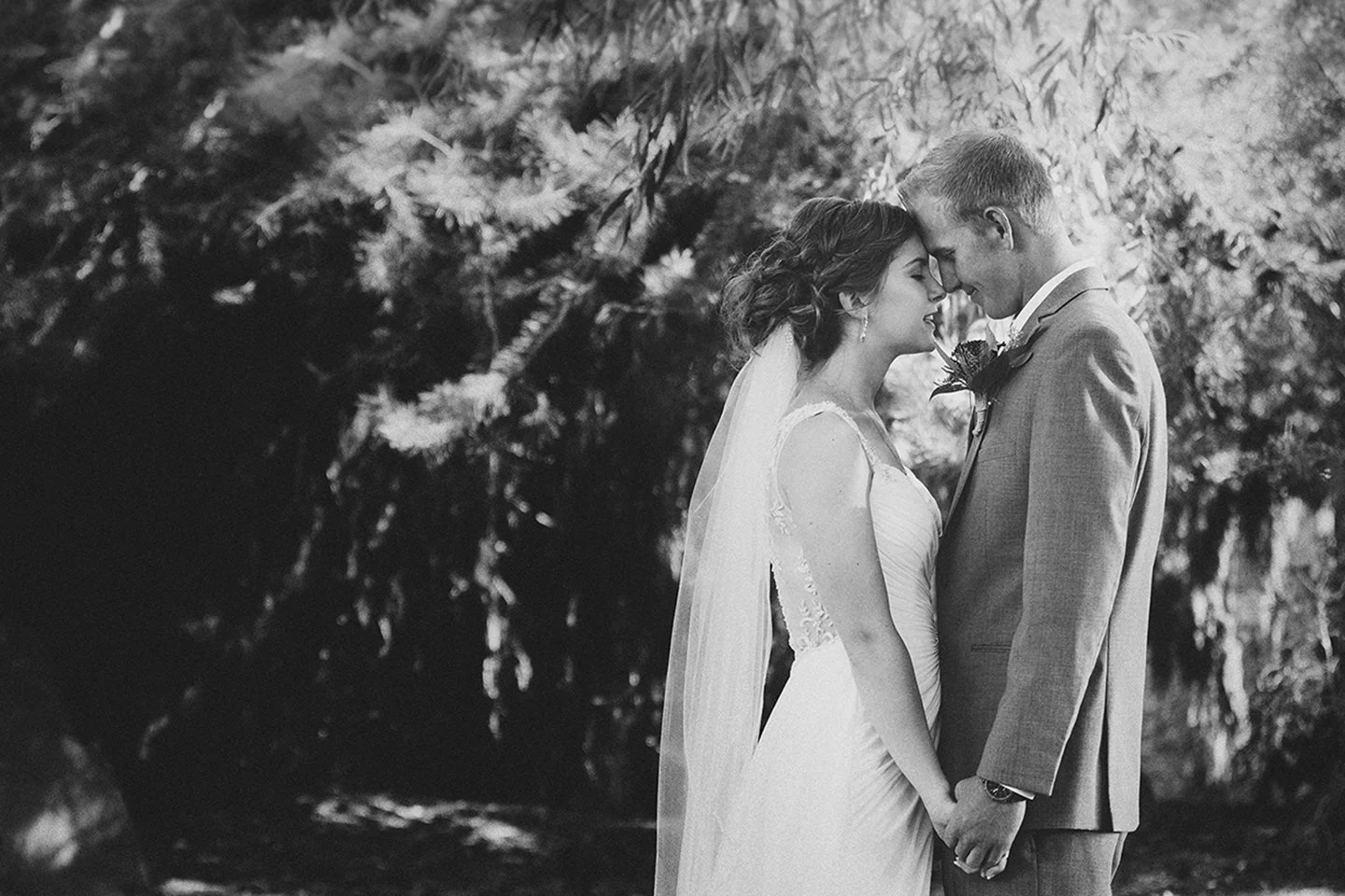 A timeless black-and-white portrait of a bride and groom at Le Jardin in Zillah, captured in a soft, emotional moment that highlights their genuine connection and the elegant garden setting.