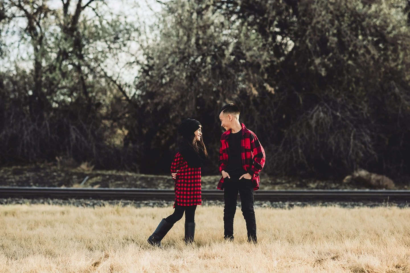 Fall sibling portraits with warm tones, dry grass, and rustic Prosser, WA train tracks.