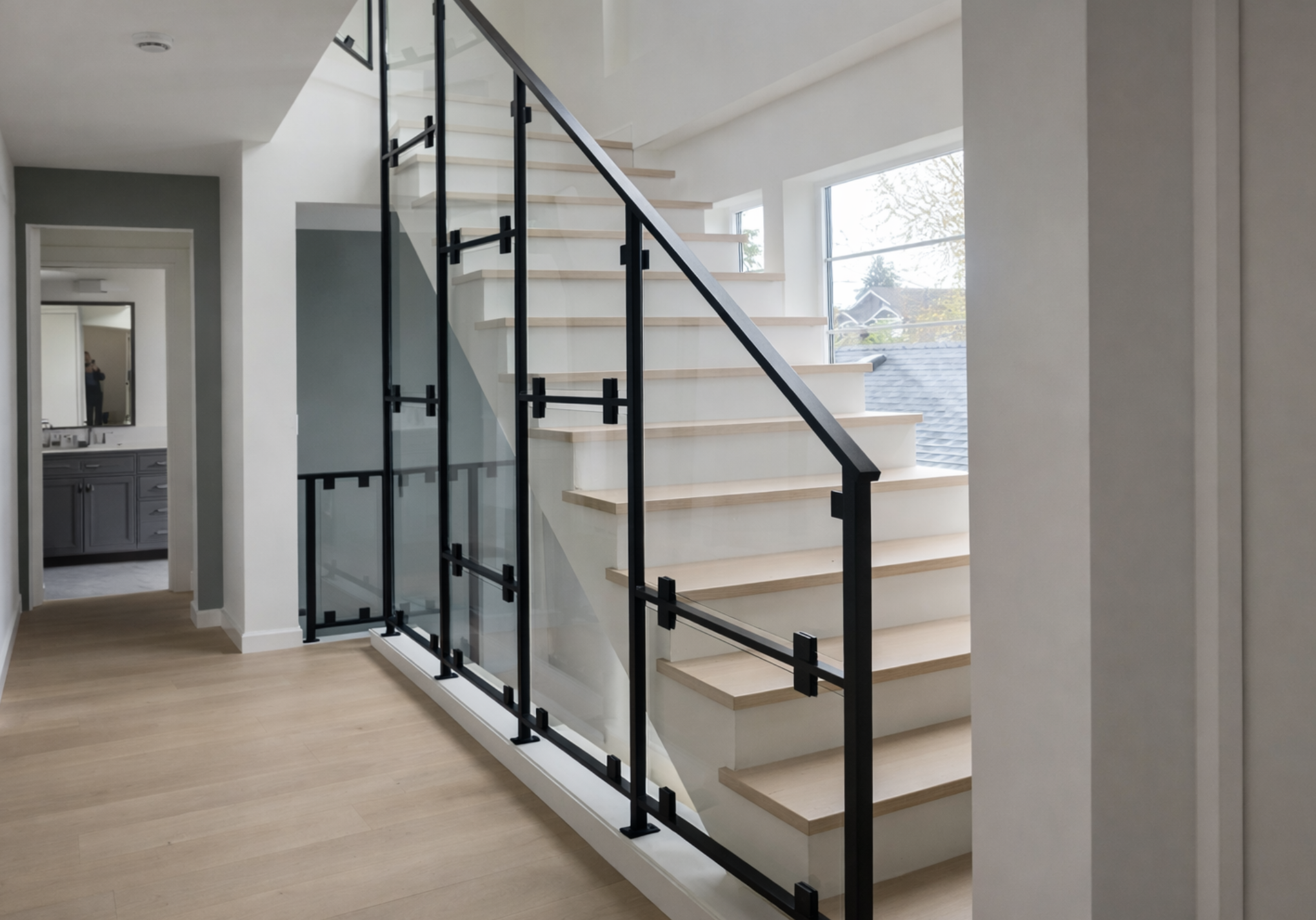 Custom glass railing with powder-coated steel frame for interior staircase