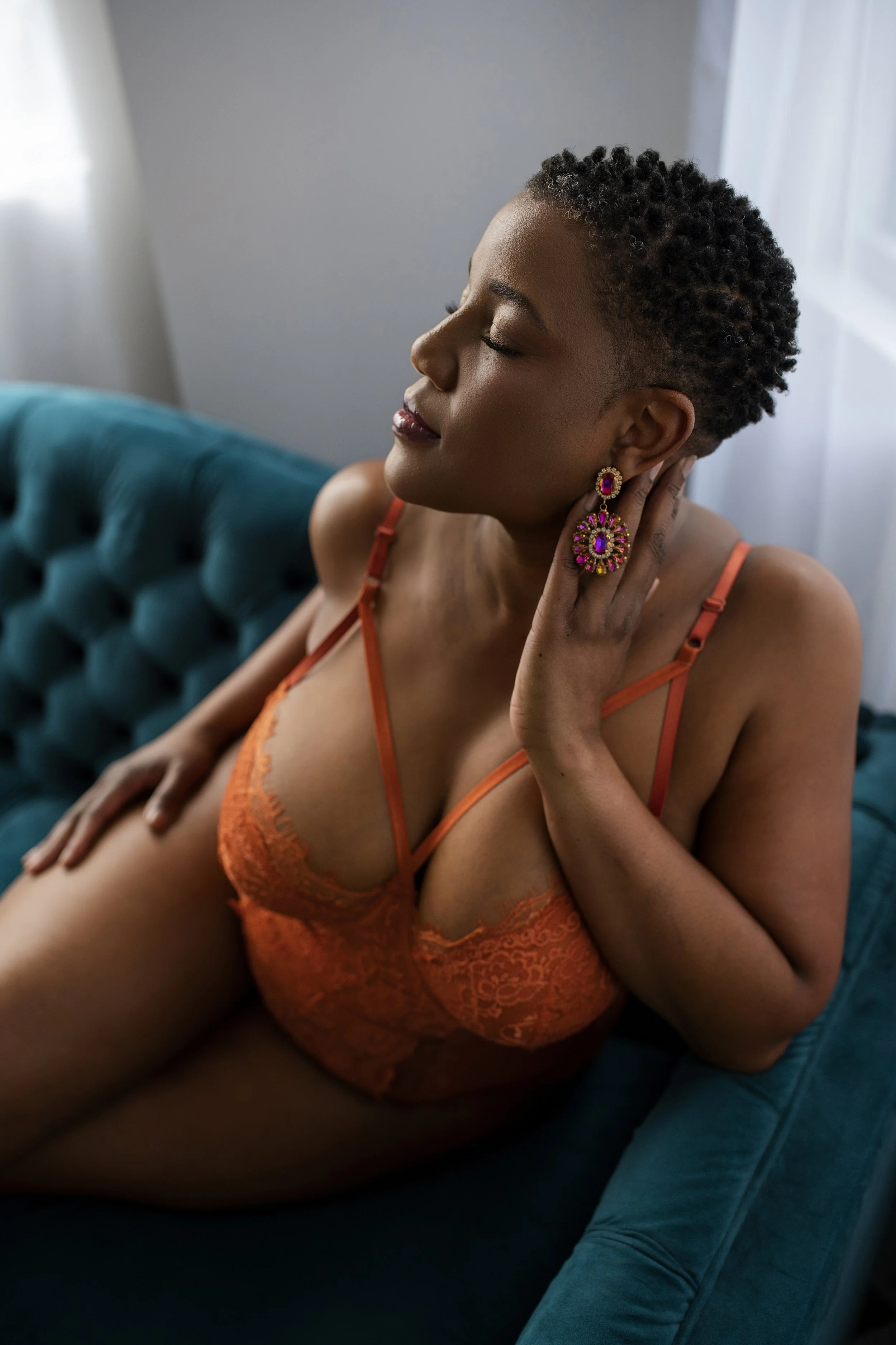 Photo of a woman with short hair in orange clothes on a teal couch.