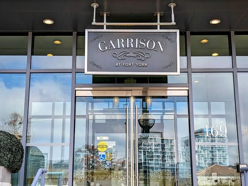 Entrance of Garrison at Fort York building, featuring a glass door with reflections, a sign above the door, and signage with the address "169 Fort York Blvd." on the right.