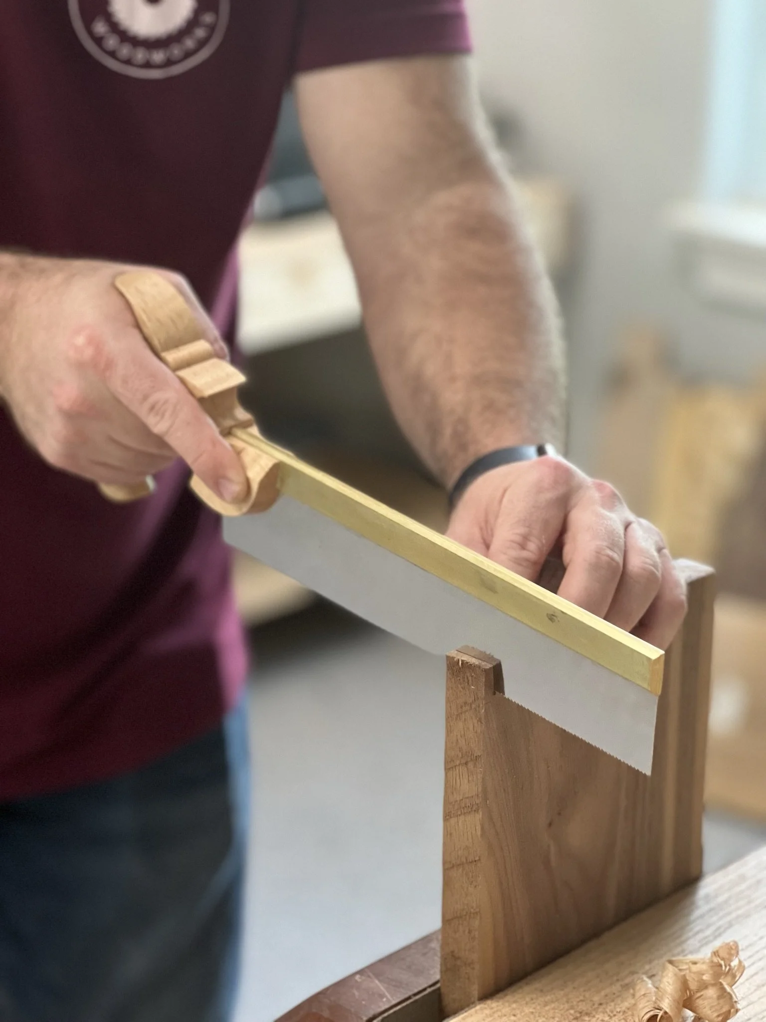 Person using a hand saw to cut dovetail joints in wooden boards