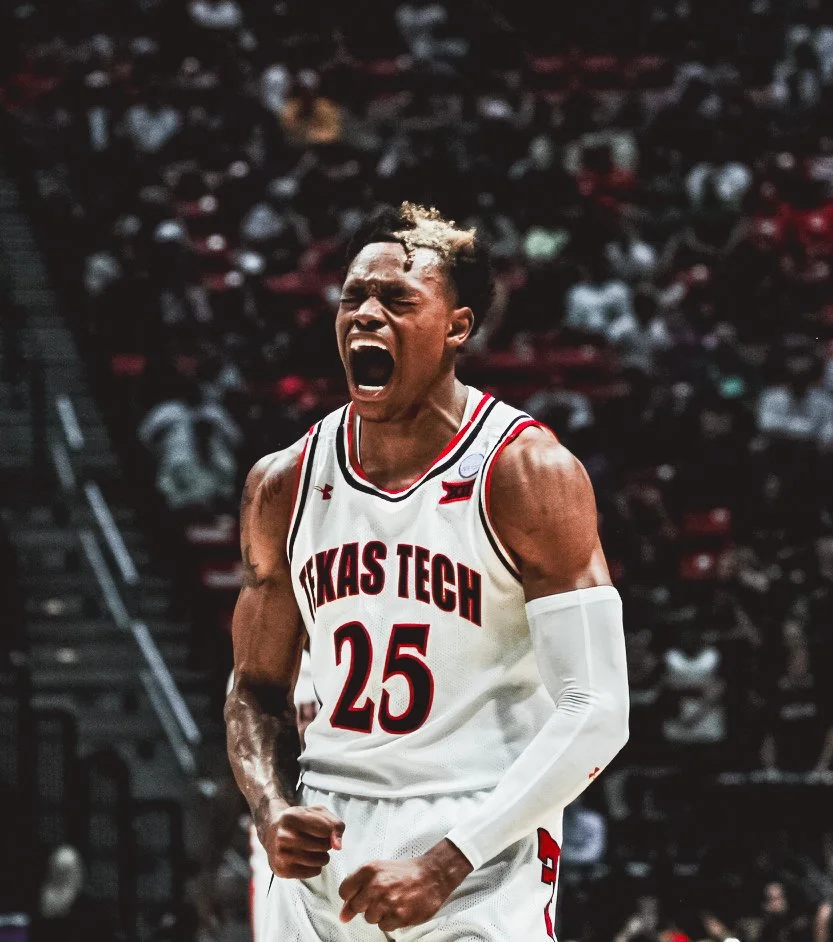 A basketball player wearing a Texas Tech uniform with the number 25 is celebrating passionately on the court, with his mouth open and fists clenched, in front of a blurred crowd.