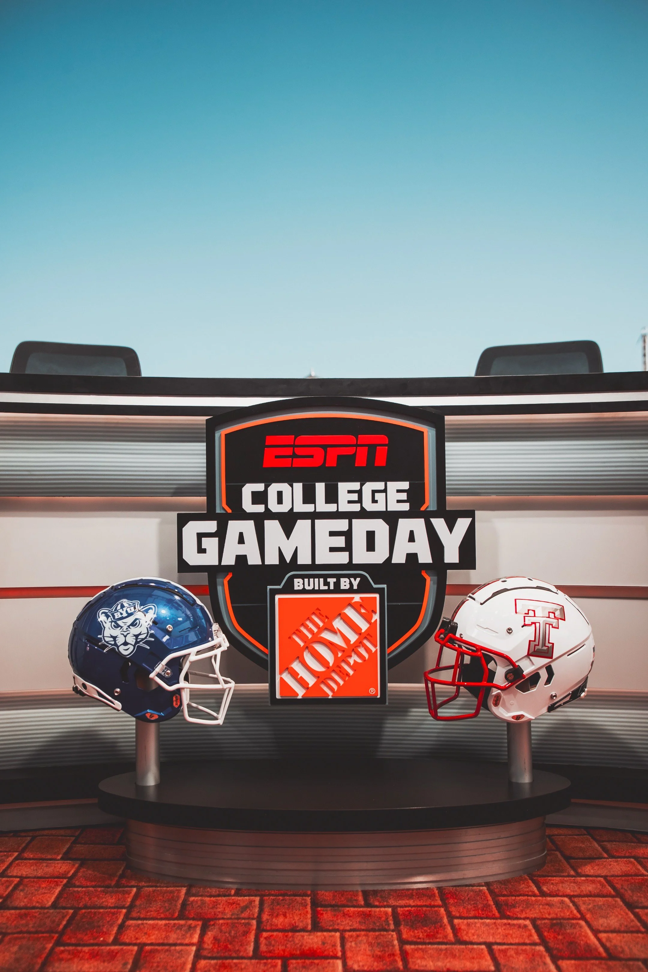 A table with two football helmets, one representing BYU and the other representing Texas Tech, with an ESPN College Gameday sign in the background.