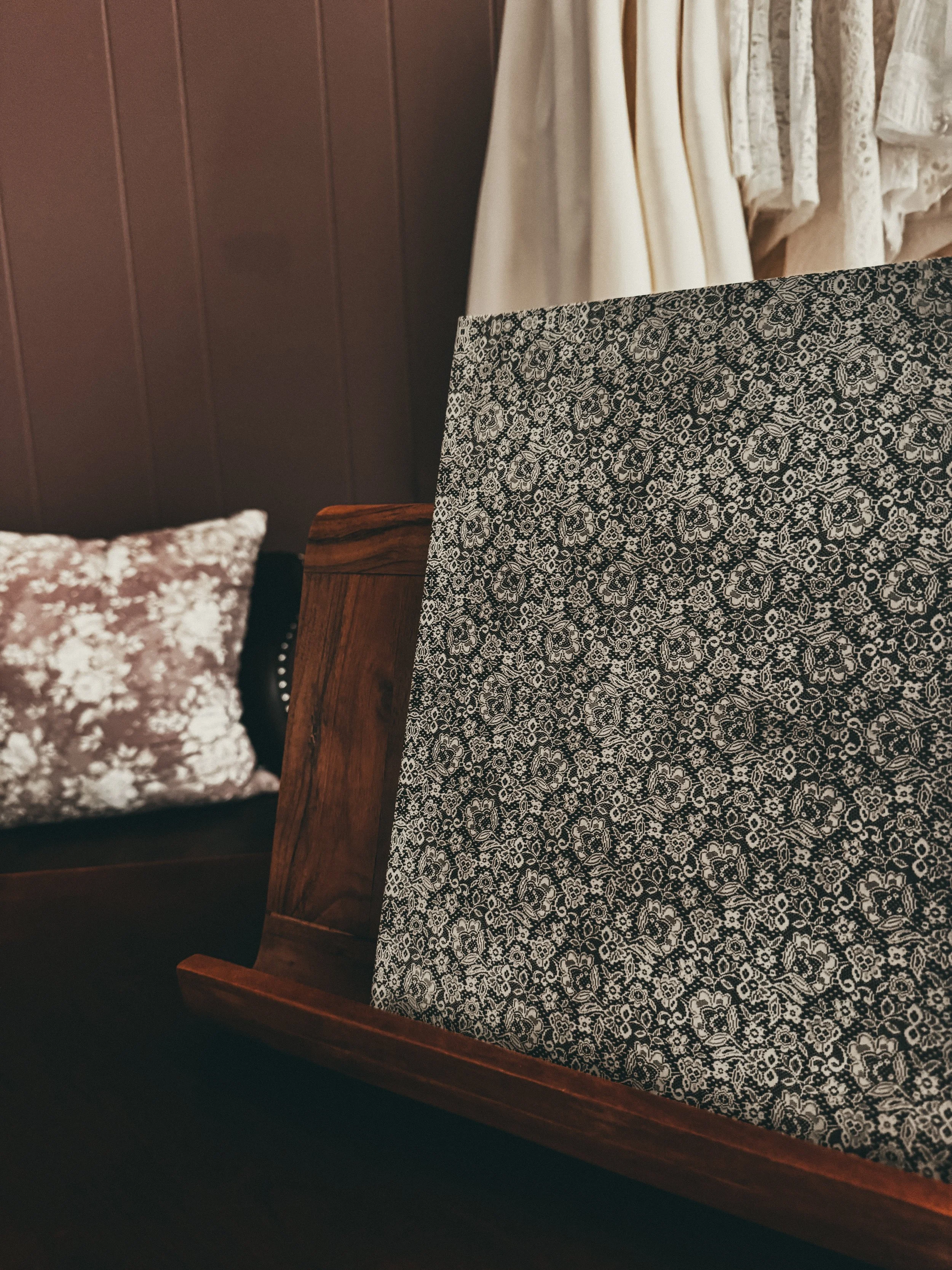 A wedding planning workbook with a dark floral hardcover, styled on a wooden ledge with a blush pillow.