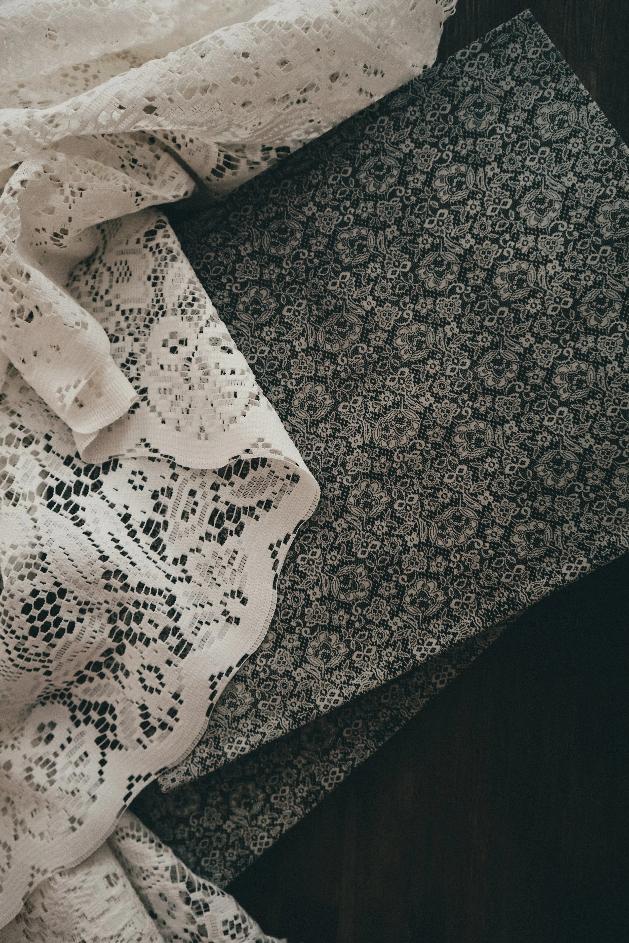 Close-up of a lace white fabric draped over a dark patterned cloth.