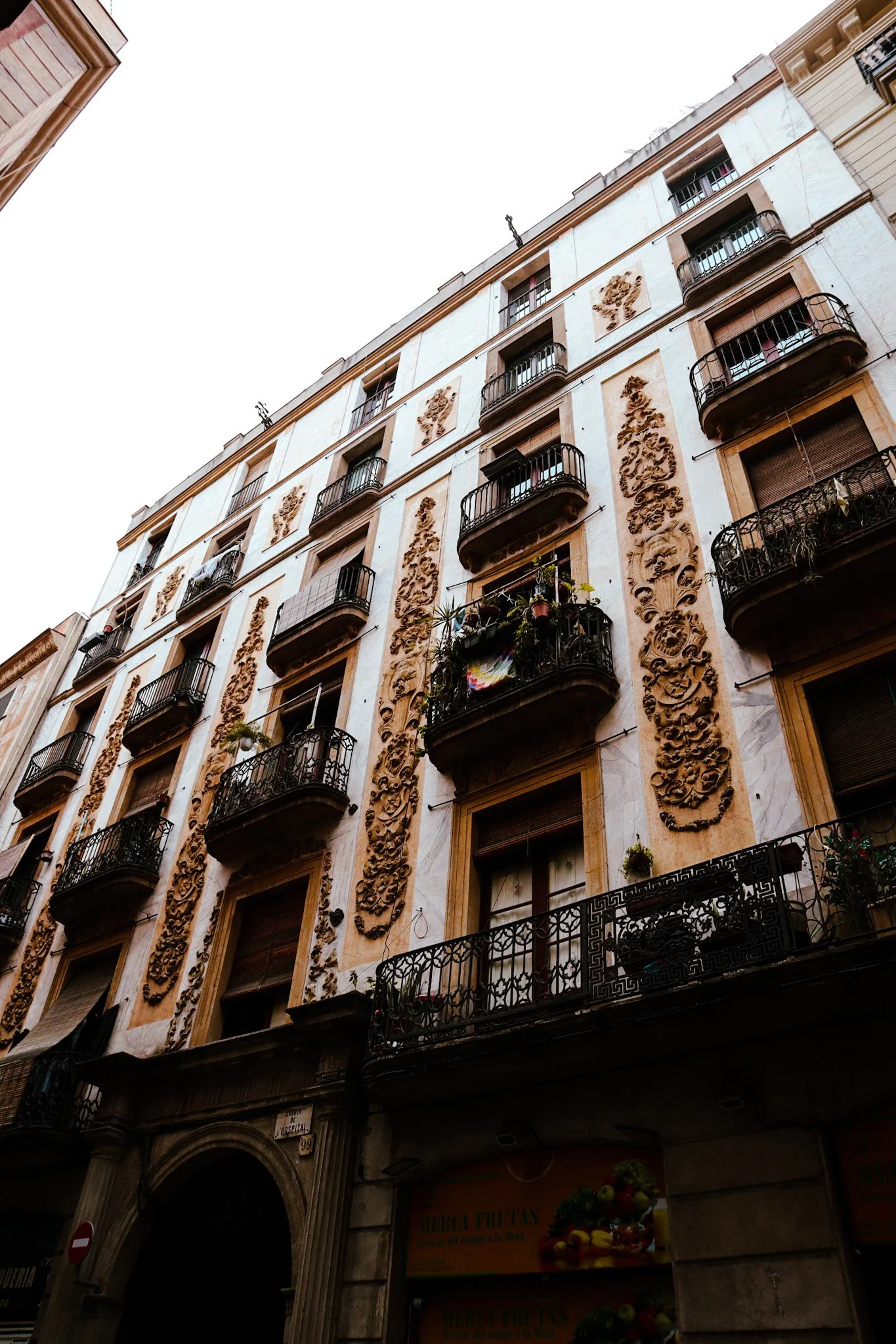A tall, ornate building with carved stone decorations and small balconies with black wrought iron railings.