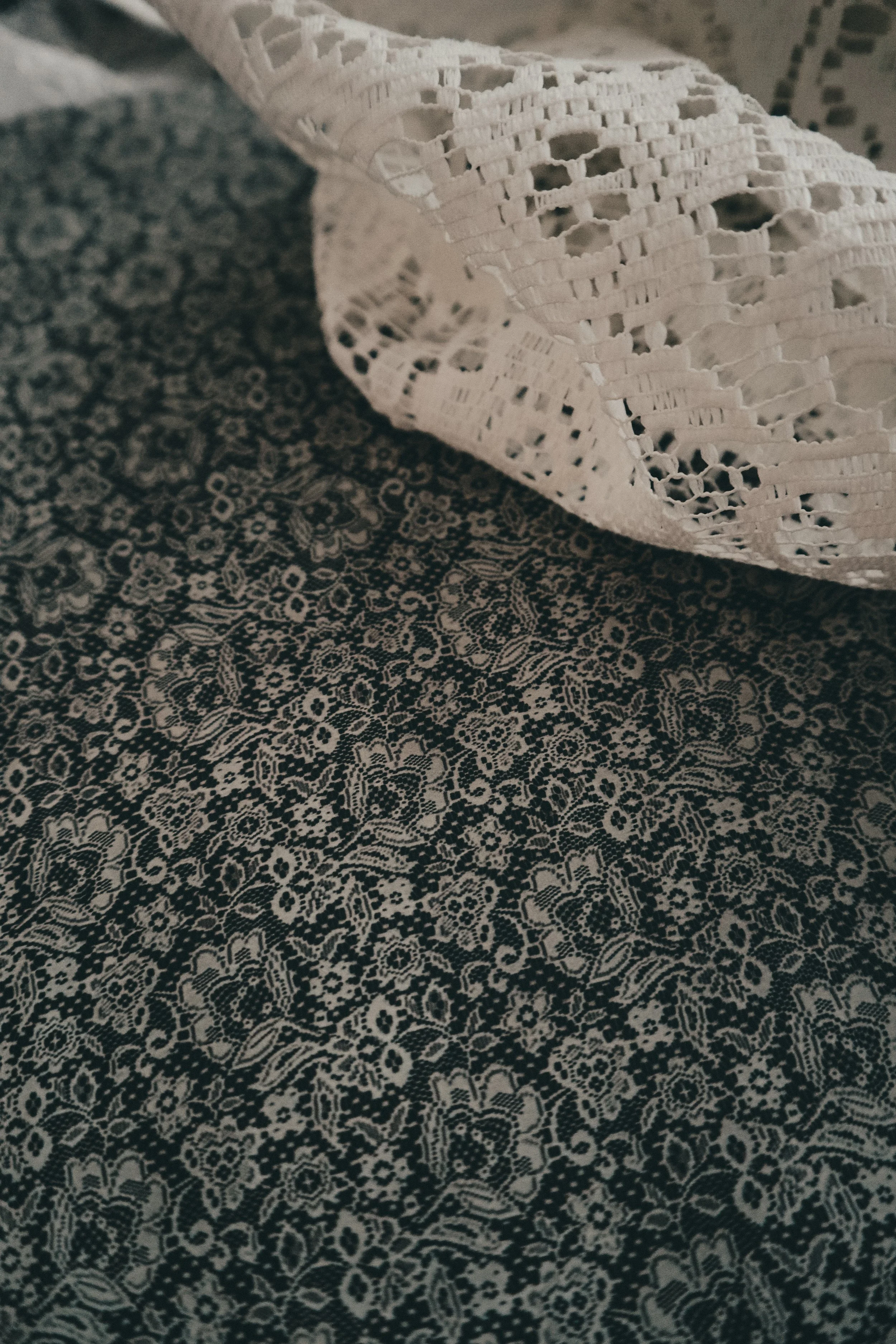 Close-up of a piece of lace fabric over a patterned textile surface.