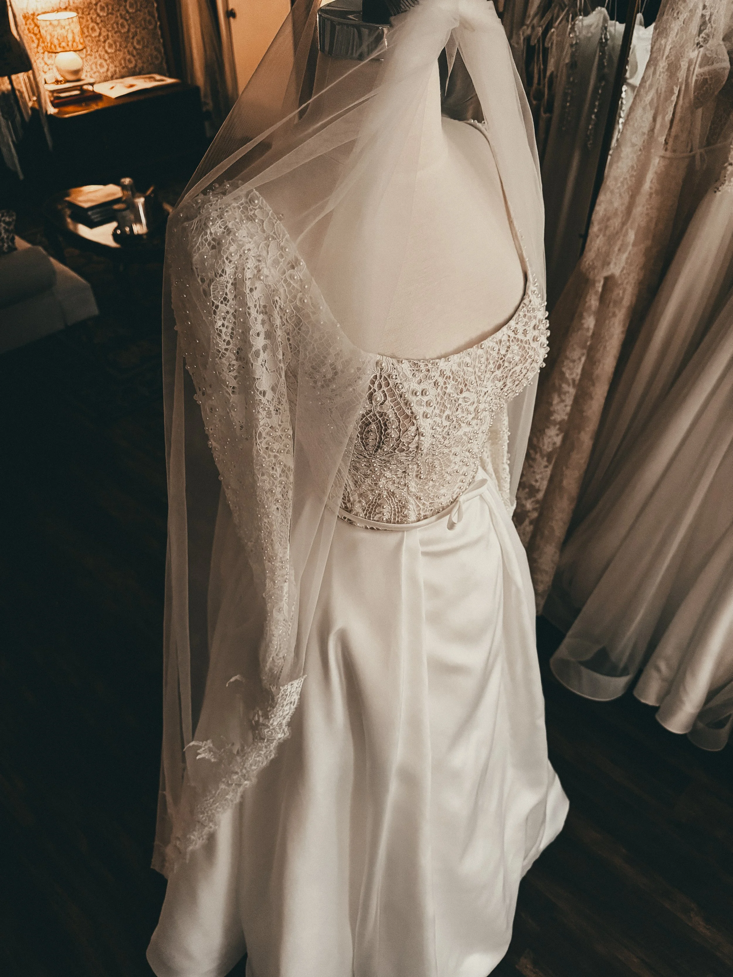 A mannequin wearing a delicate lace bodice with pearl beading, styled with soft veiling at Art & Lace Bridal in Somerset, Massachusetts.